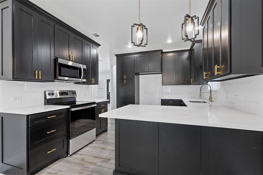 Kitchen featuring sink, tasteful backsplash, appliances with stainless steel finishes, and light hardwood / wood-style floors