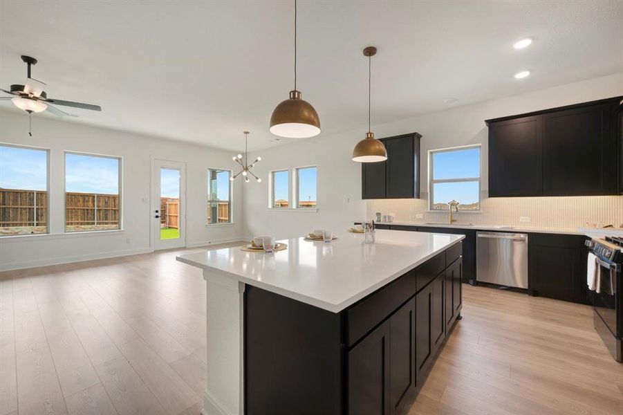 Kitchen featuring dark cabinets, light wood-style flooring, backsplash, a center island, and stainless steel appliances Kitchen featuring dark cabinets, light wood-style flooring, backsplash, a center island, and stainless steel appliances