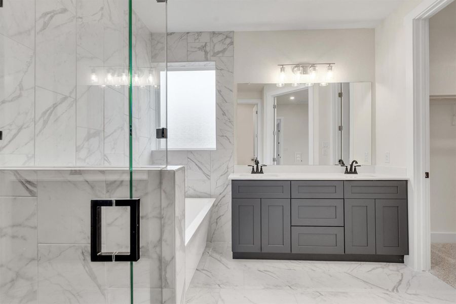 Marble-clad bathroom features a sleek double vanity, a deep soaking tub, and a spacious glass-enclosed shower.
