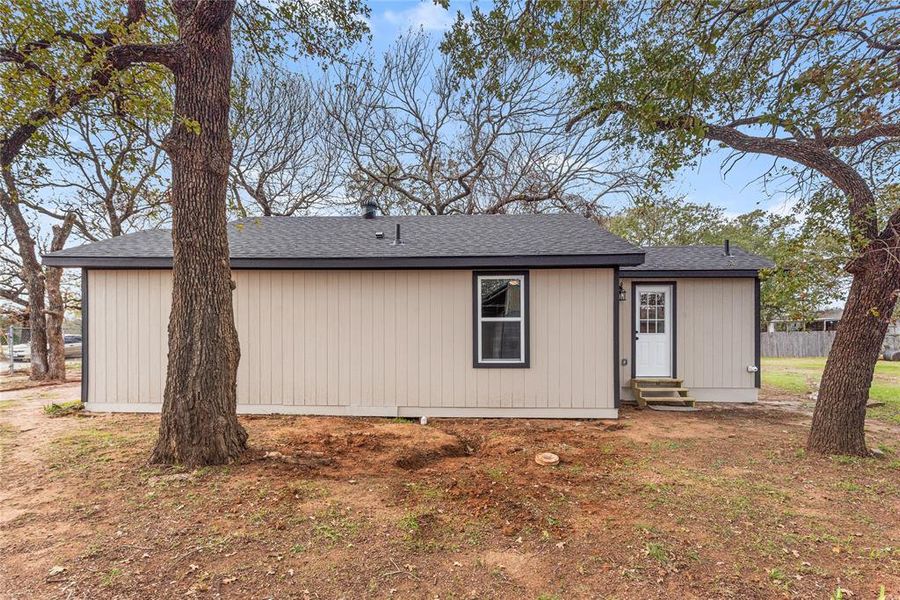 Rear view of property featuring entry steps and roof with shingles
