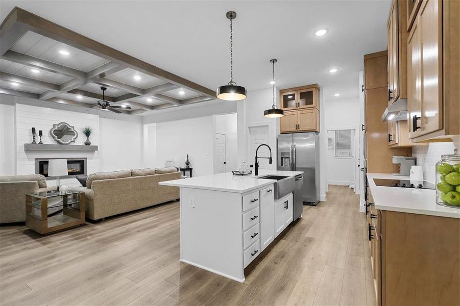 Kitchen featuring white cabinets, sink, stainless steel fridge with ice dispenser, an island with sink, and light wood-type flooring