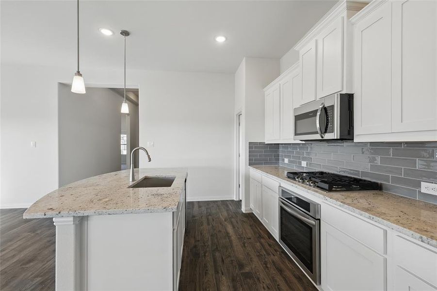 Kitchen featuring light stone counters, a kitchen island with sink, white cabinets, and stainless steel appliances