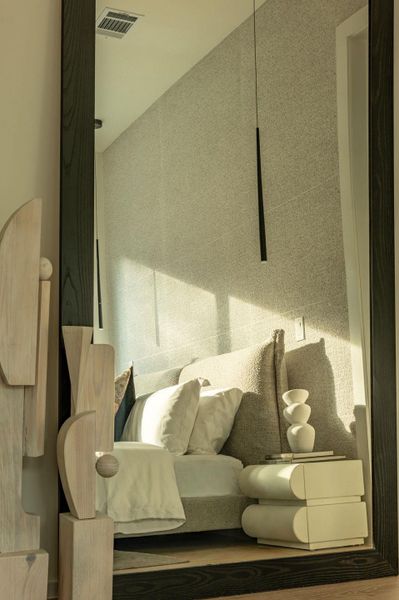 A textured accent wall anchors the room with soft depth and warmth, creating a serene, modern backdrop for the cozy bedroom setting