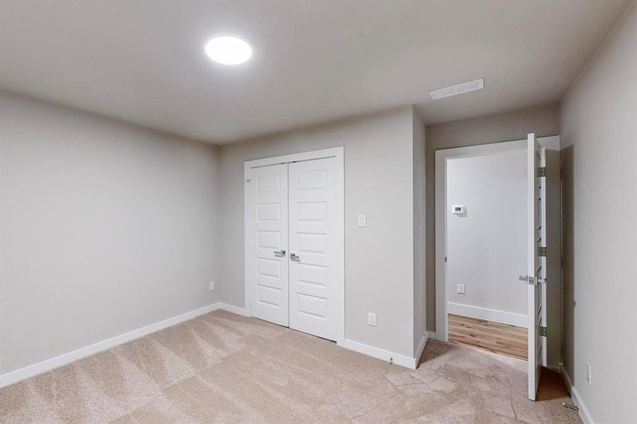 Unfurnished bedroom with light carpet and a closet