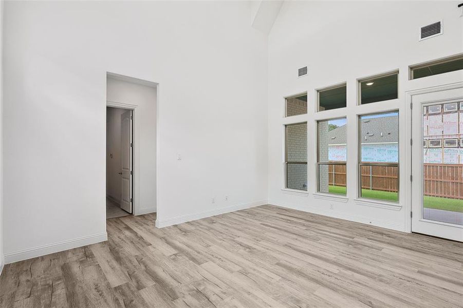 Spare room featuring a wealth of natural light, light hardwood / wood-style flooring, and a high ceiling