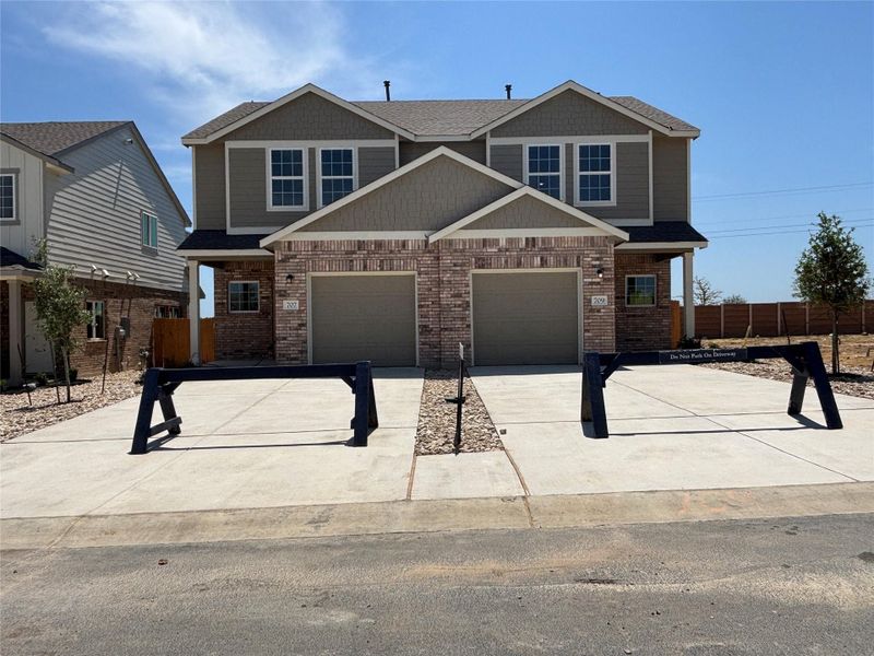 Craftsman house featuring brick siding, concrete driveway, an attached garage, fence, and roof with shingles