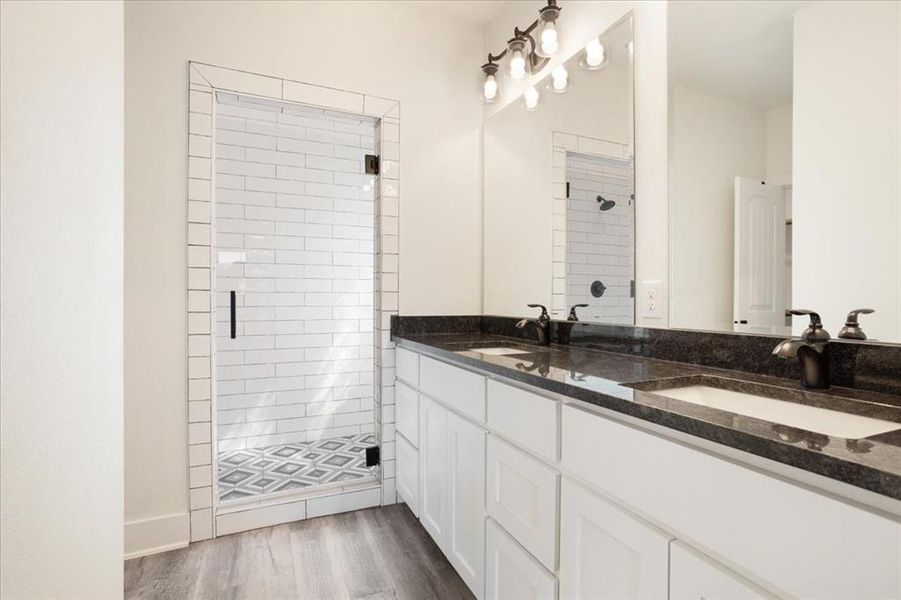 Master bath featuring a shower stall, double vanity, and wood-type flooring