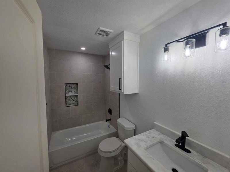 Full bath with vanity, washtub / shower combination, a textured ceiling, a textured wall, and wood finished floors Full bath with vanity, washtub / shower combination, a textured ceiling, a textured wall, and wood finished floors