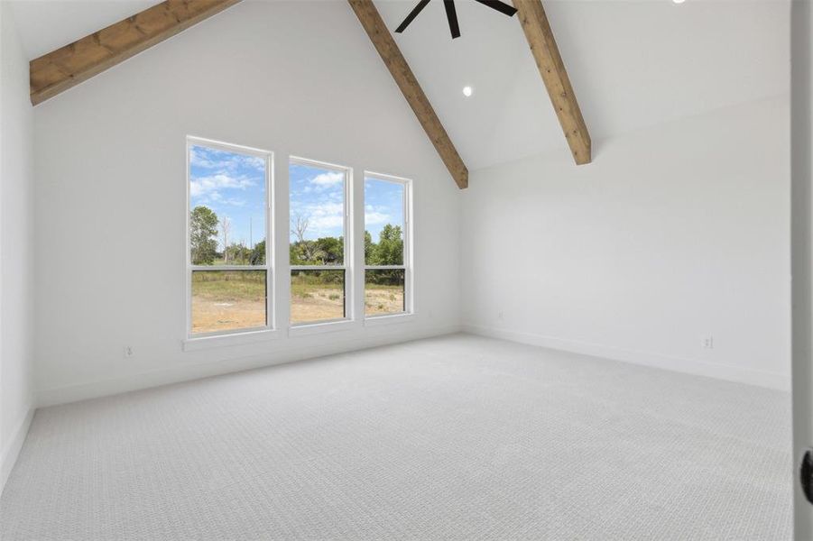 Empty room featuring beamed ceiling, carpet, and high vaulted ceiling