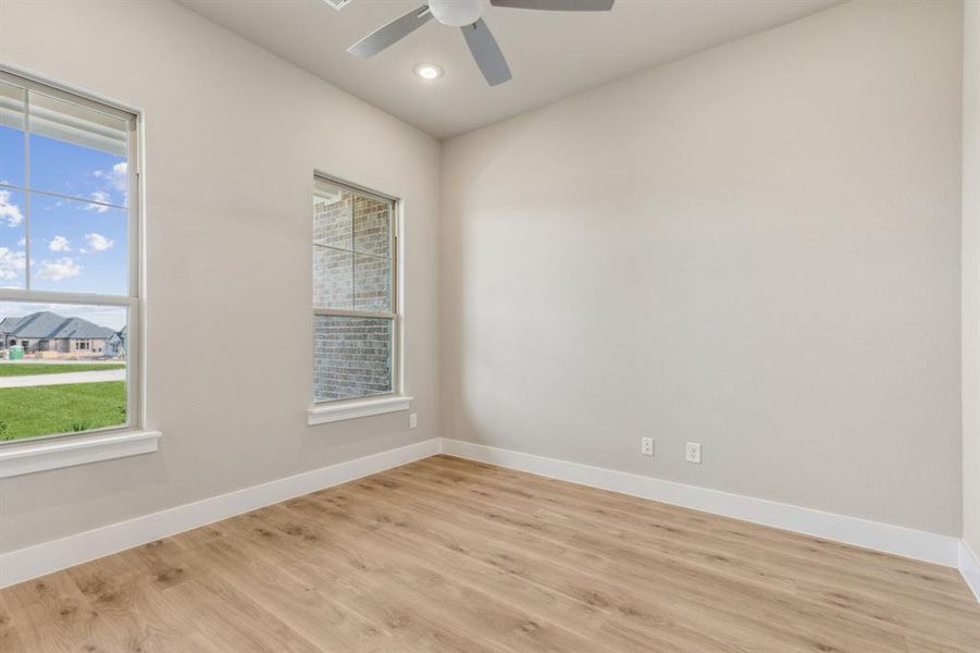 Empty room featuring ceiling fan, a healthy amount of sunlight, and light hardwood / wood-style flooring