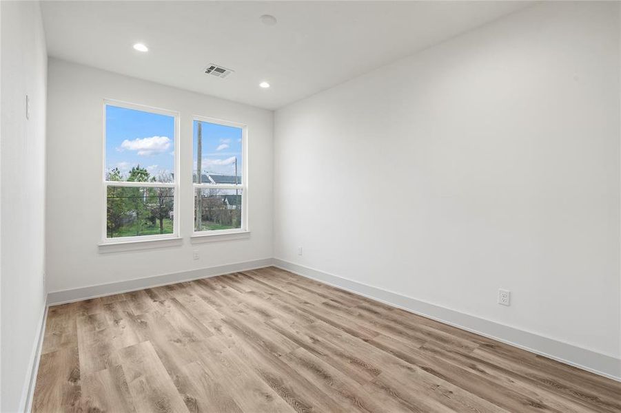 Another spacious and inviting secondary bedroom, designed with high ceilings and large windows that flood the room with natural light.