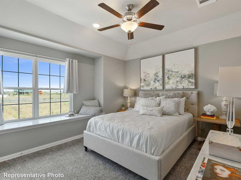 Bedroom featuring a coffered ceiling with a ceiling fan, a large window with gridded panes, a built-in window seat, and gray carpet flooring
