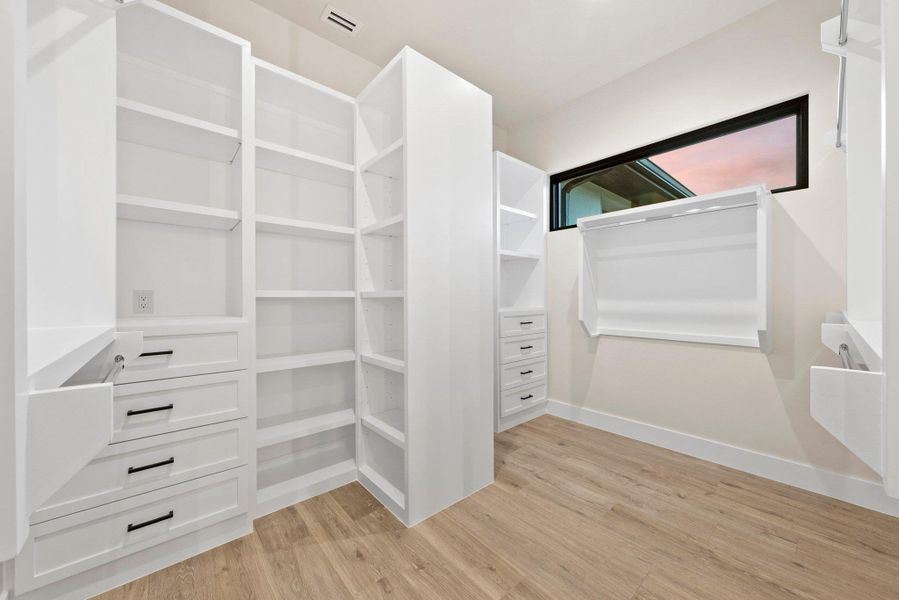 Custom shelving and drawers provide ample storage in this well-appointed walk-in closet.