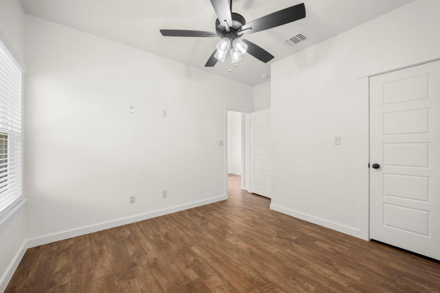 A well-lit room showcasing rich hardwood flooring and a modern ceiling fan for comfort.