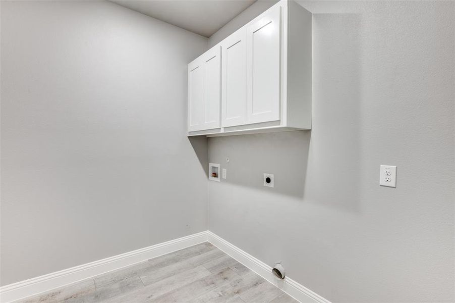 Clothes washing area featuring washer hookup, cabinets, light hardwood / wood-style floors, and hookup for an electric dryer