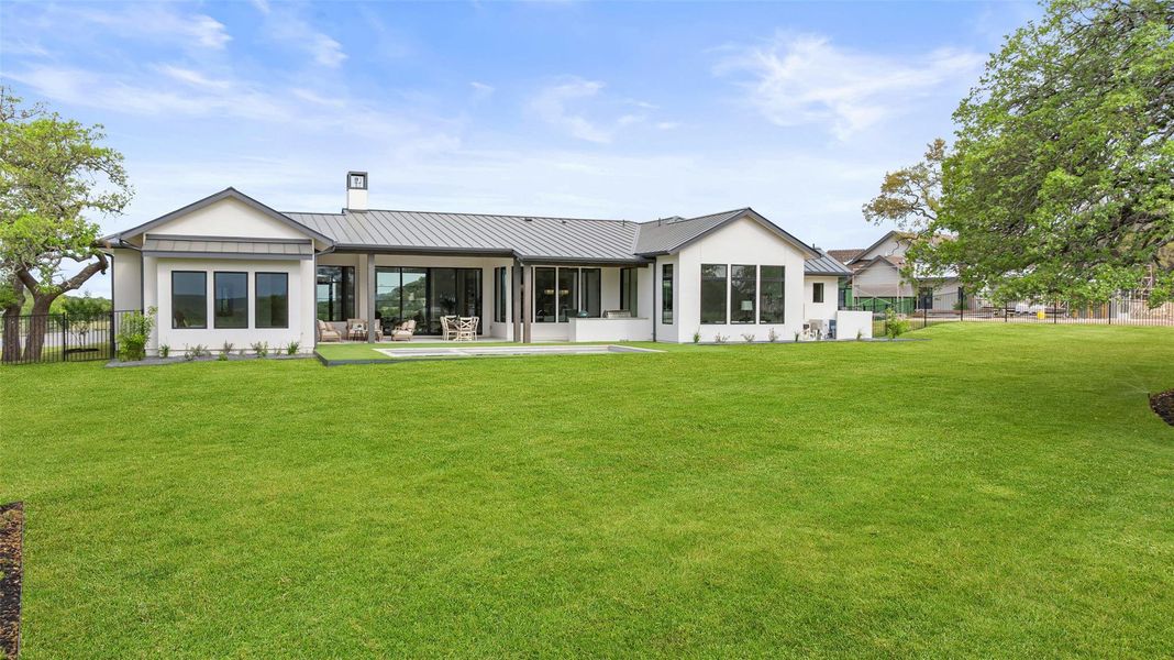 Rear view of house featuring a standing seam roof, a chimney, fence, a lawn, and a sunroom Rear view of house featuring a standing seam roof, a chimney, fence, a lawn, and a sunroom