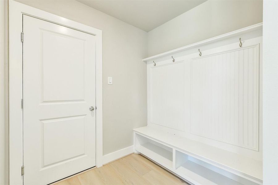 Mudroom drop zone located near the garage entry features built-in hooks and bench seating with storage below.