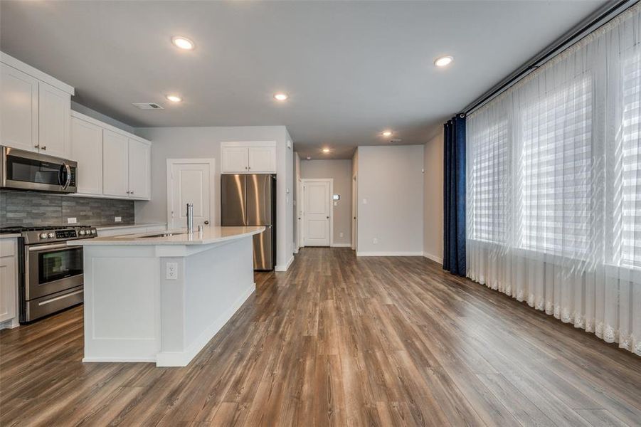 Kitchen featuring visible vents, dark wood finished floors, a sink, stainless steel appliances, and tasteful backsplash