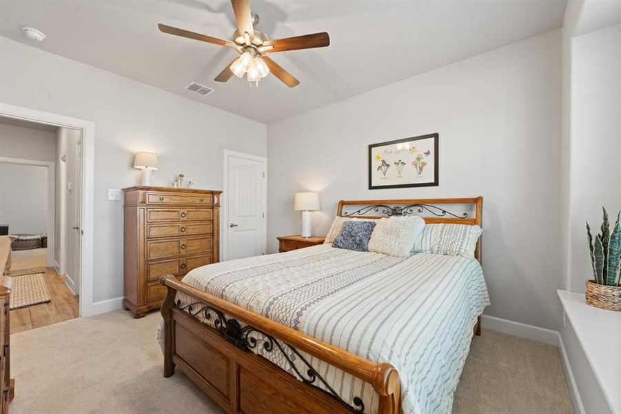 Bedroom with light carpet, a ceiling fan, and a closet