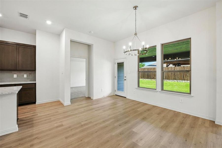 Unfurnished dining area with a chandelier, light wood-style flooring, and recessed lighting