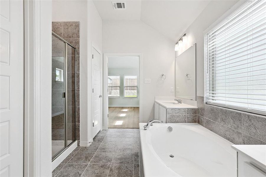 Bathroom featuring tile floors, separate shower and tub, vanity, and vaulted ceiling