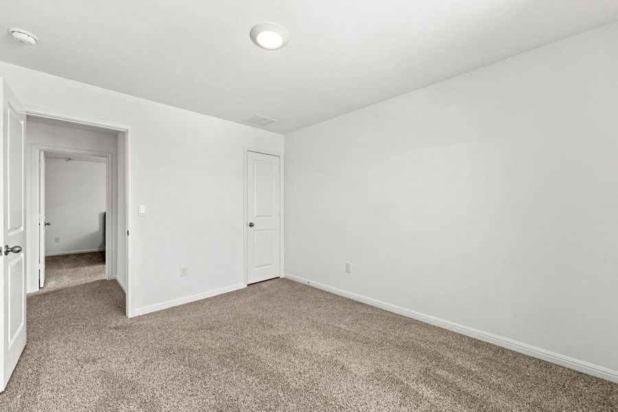Plush wall-to-wall carpeting and crisp white walls define this versatile, neutral bedroom space.
