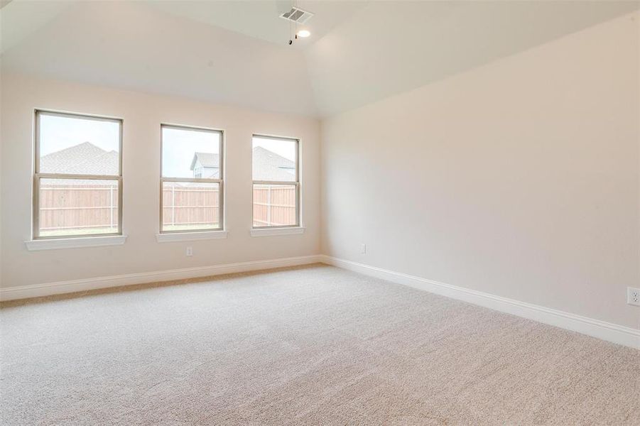 Carpeted spare room featuring vaulted ceiling