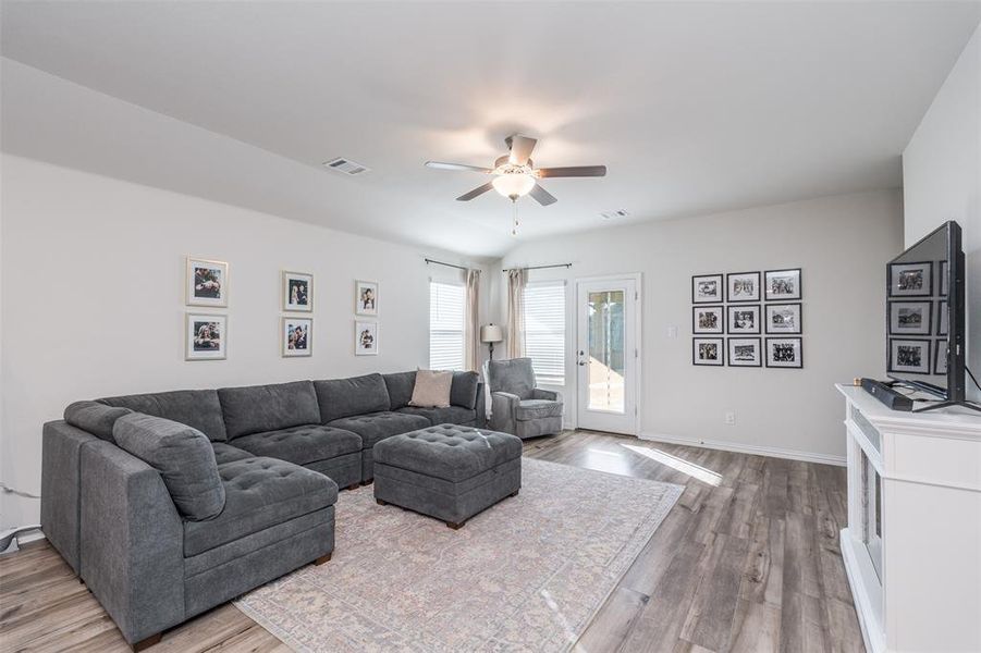 Living room with baseboards, ceiling fan, visible vents, and wood finished floors