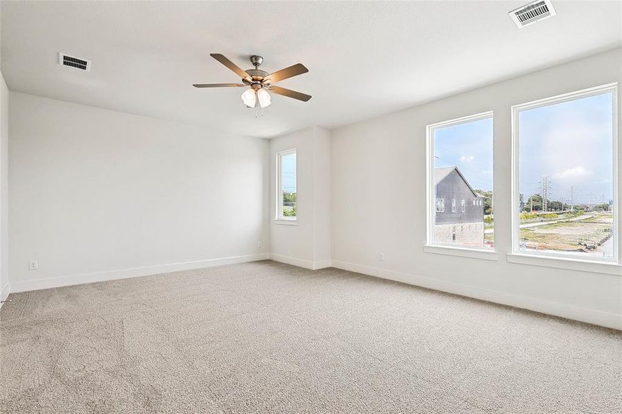 Empty room featuring ceiling fan and light carpet