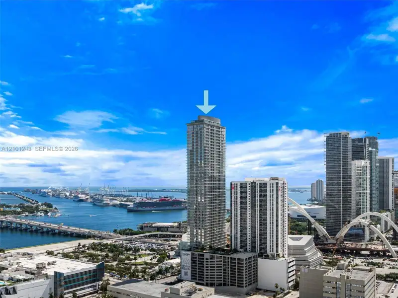 High-rise residential tower featuring a glass facade, private balconies, and a multi-level parking structure High-rise residential tower featuring a glass facade, private balconies, and a multi-level parking structure