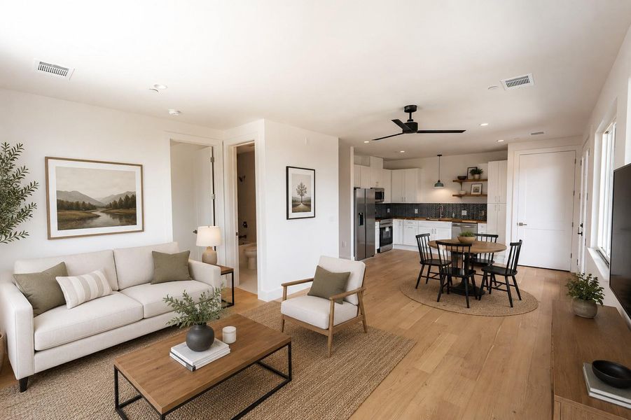An open-concept living space with light wood flooring flows seamlessly into a modern kitchen and dining area. (virtually staged) An open-concept living space with light wood flooring flows seamlessly into a modern kitchen and dining area. (virtually staged)