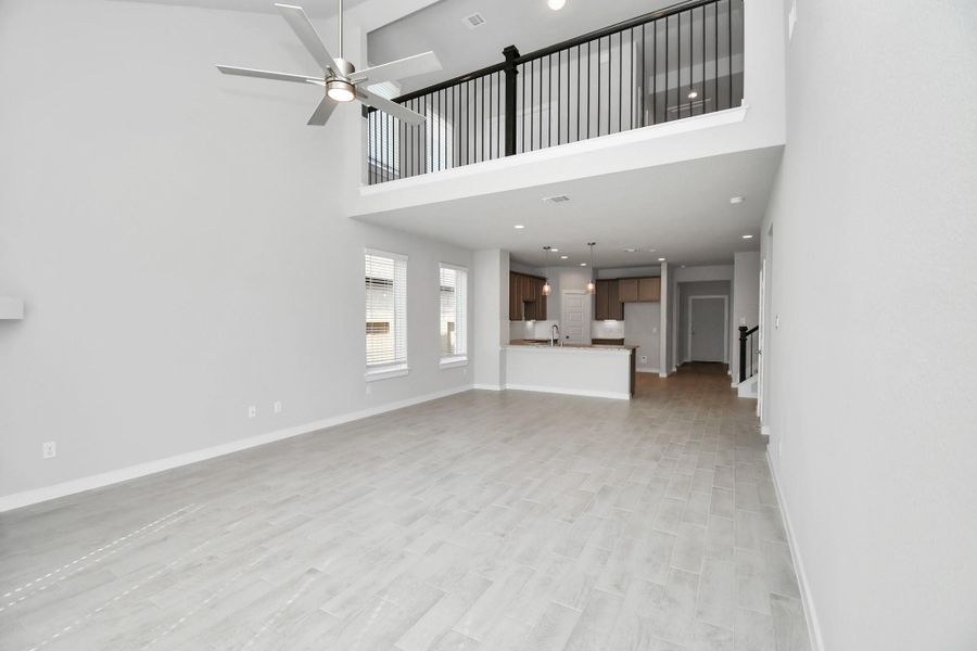 Bring your loved ones and guests together in the inviting living room! Boasting lofty high ceilings, recessed lighting, a stylish ceiling fan, custom paint, stunning flooring, and expansive windows that flood the space with ample natural light all day long. Sample photo of completed home with similar floor plan. Actual colors and selections may vary.