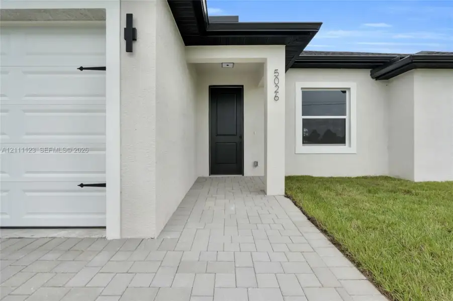 Front entry with black door and paved walkway.