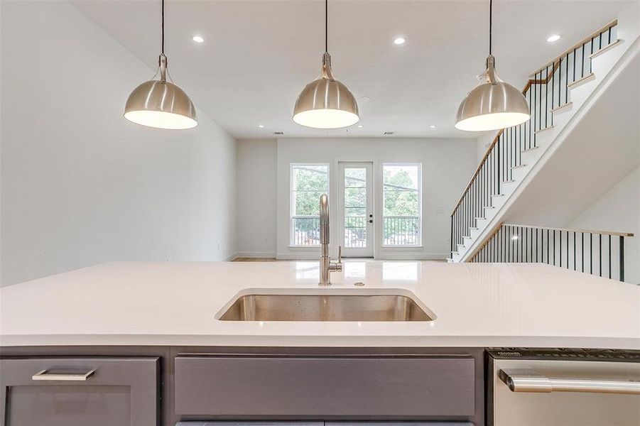 Kitchen featuring a sink, gray cabinetry, pendant lighting, and light countertops