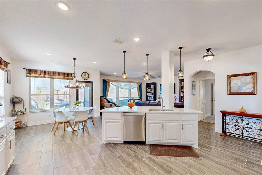 Kitchen with open floor plan, hanging light fixtures, white cabinets, ceiling fan, and stainless steel dishwasher