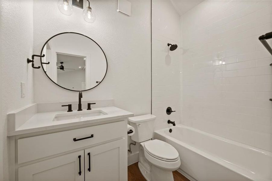 Bathroom with vanity, washtub / shower combination, wood finished floors, and a textured wall Bathroom with vanity, washtub / shower combination, wood finished floors, and a textured wall
