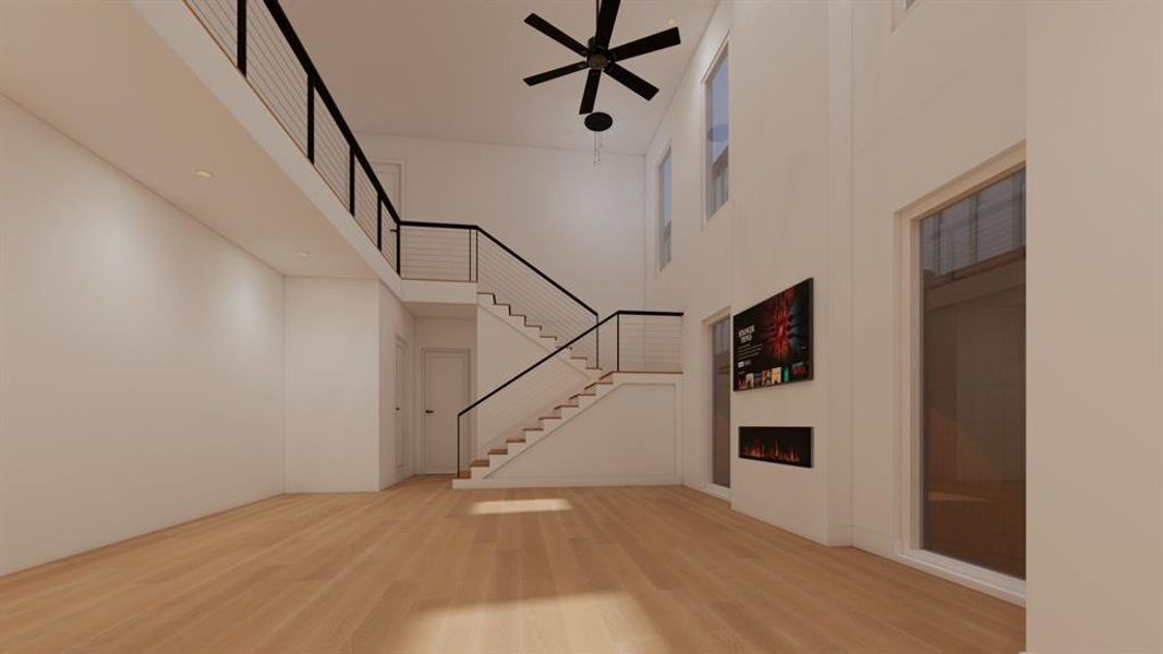 Entryway with a high ceiling, light wood finished floors, a lit fireplace, and a ceiling fan
