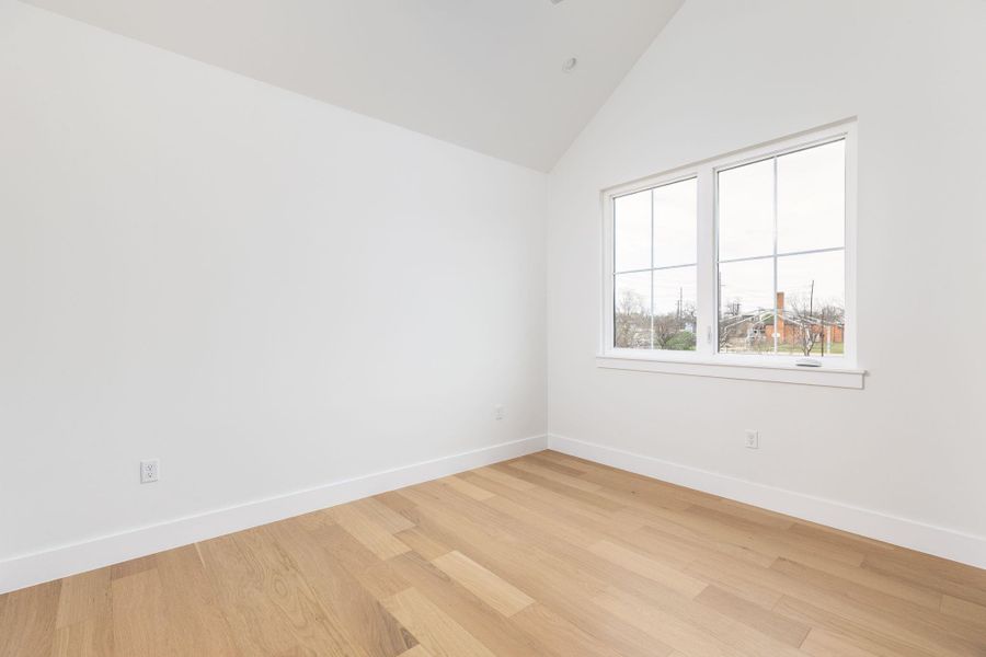 Unfurnished room featuring light wood-style flooring and lofted ceiling
