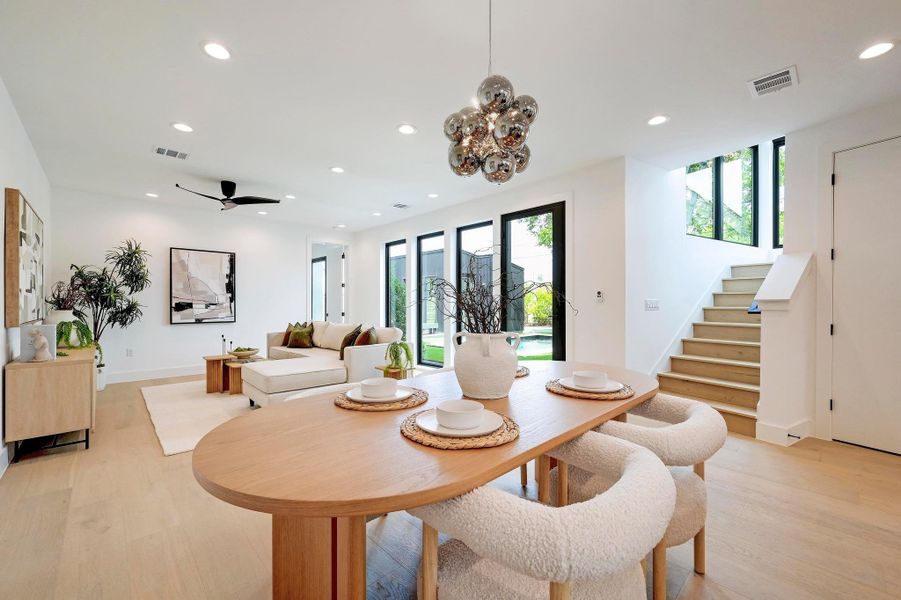 Dining room with recessed lighting, light wood-type flooring, healthy amount of natural light, stairs, and a chandelier