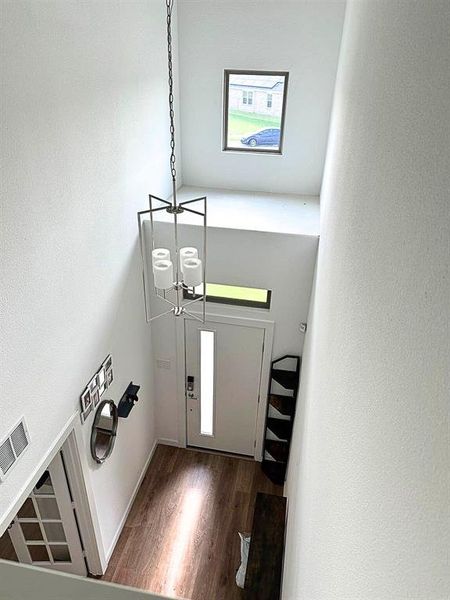 Foyer entrance with dark wood-style floors and a chandelier