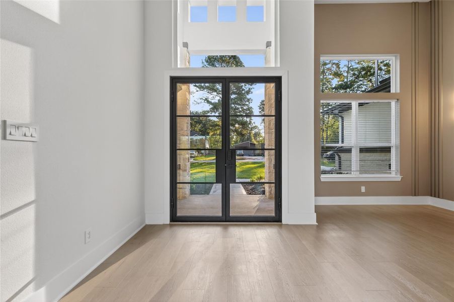 Dramatic foyer welcomes you with soaring ceilings, oversized windows, and a sleek contemporary front door. **Images are from a previously completed project. **