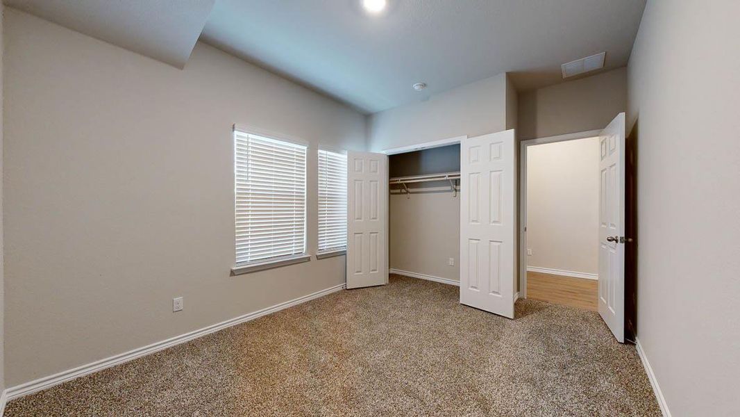 Unfurnished bedroom with light carpet and a closet