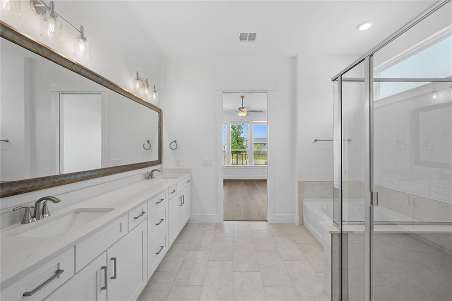 Bright bathroom featuring a dual vanity with quartz countertops, integrated sinks, white cabinetry, and brushed nickel hardware