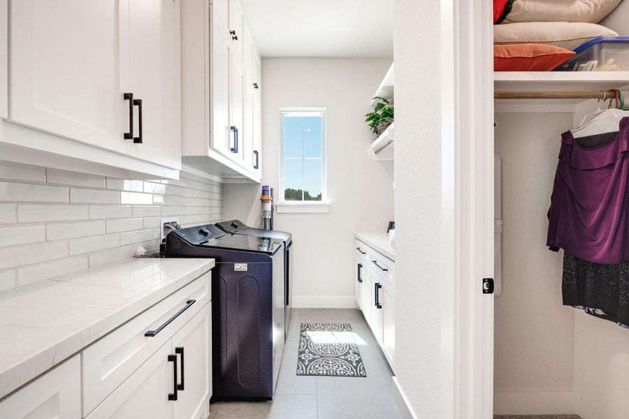 Laundry room with cabinet space, light tile patterned flooring, and independent washer and dryer