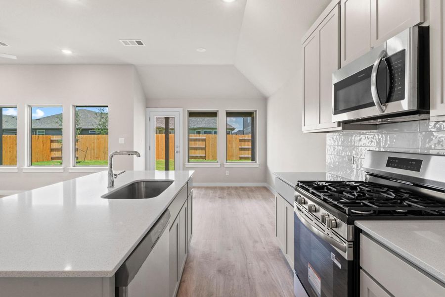A well-appointed kitchen features an island with a sink, sleek countertops, and modern stainless steel appliances.