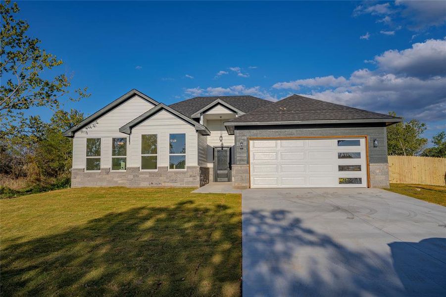 View of front of property featuring a front yard and a garage