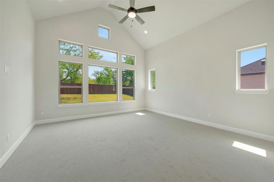 Empty room featuring a high ceiling, carpet flooring, a ceiling fan, plenty of natural light, and recessed lighting