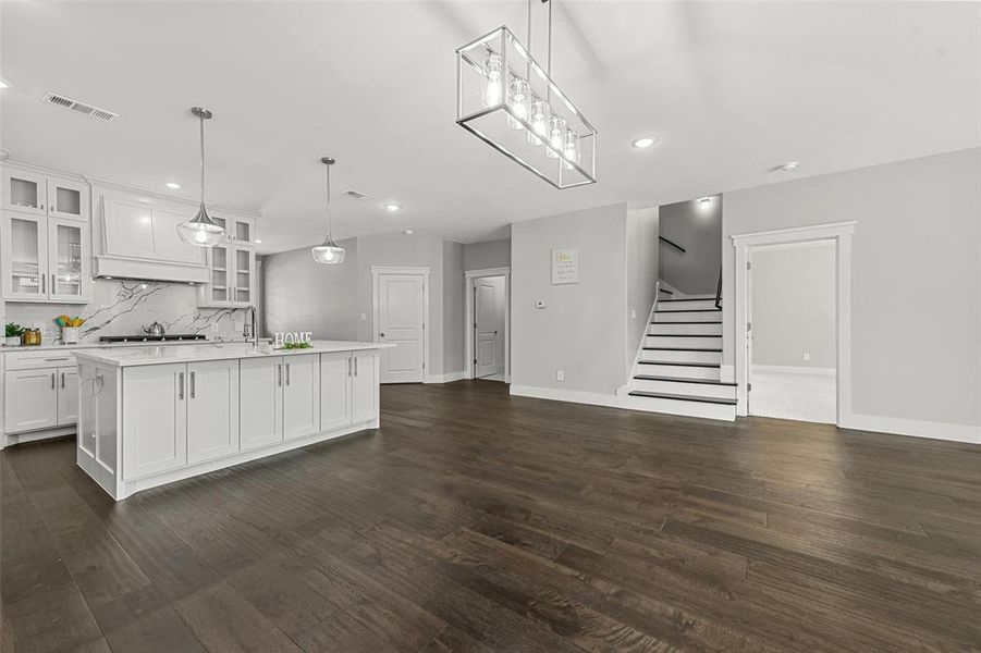 Kitchen featuring an island with sink, white cabinetry, decorative light fixtures, and dark hardwood / wood-style floors