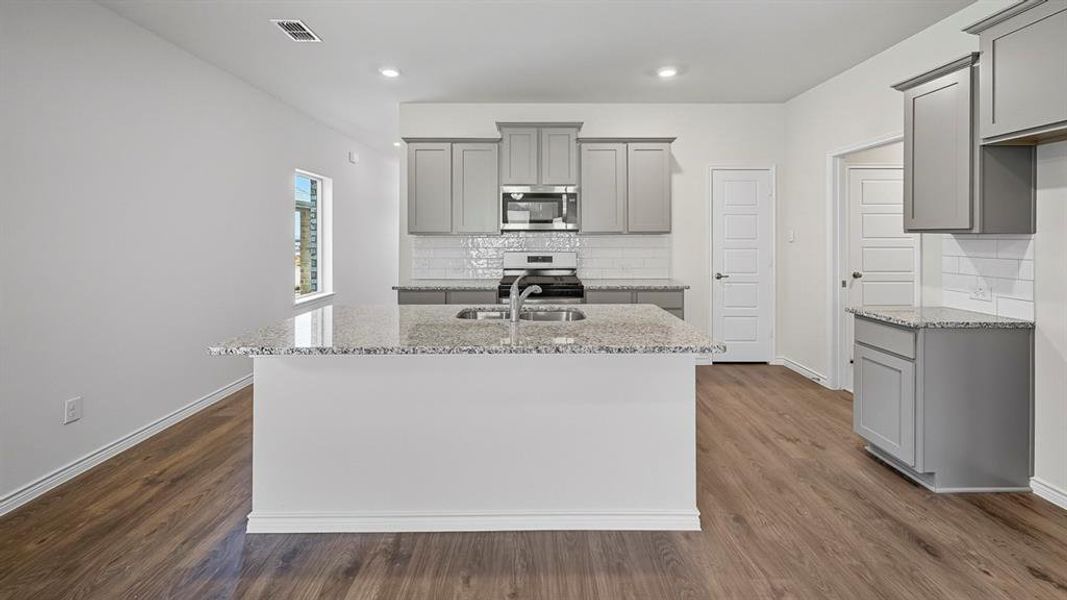 Kitchen with gray cabinets, light stone countertops, tasteful backsplash, and recessed lighting