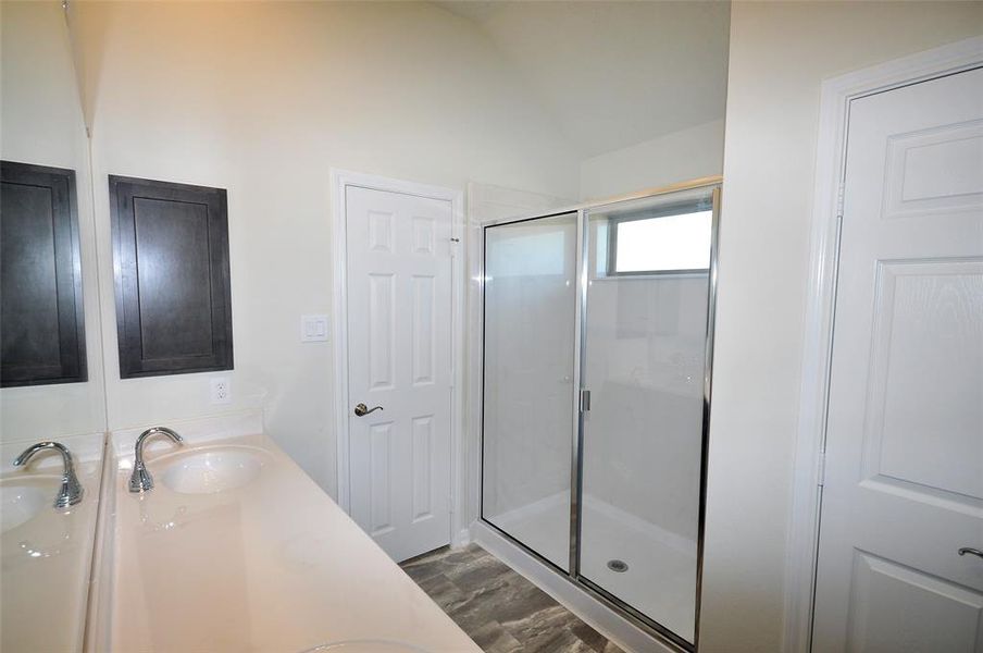 Oversized walk in shower is surrounds with clear glass door and cultured Marble surrounds.